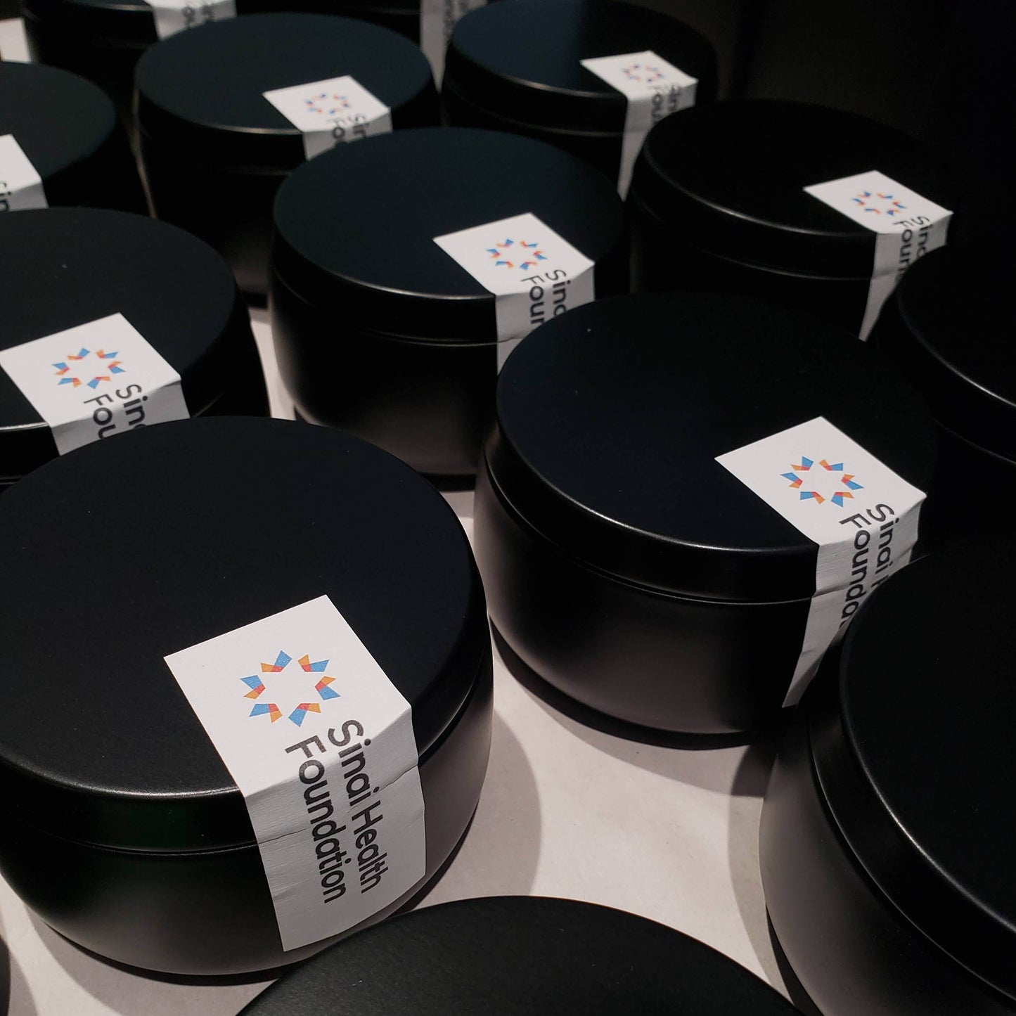 8oz black tin custom candles in production for client & employee gifts