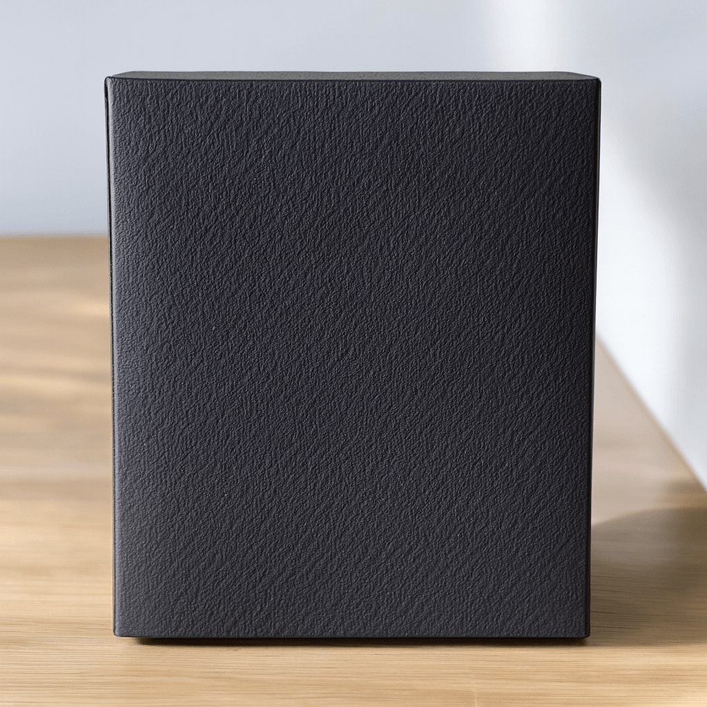 Black textured blank gift box on a wooden surface with a light gray background
