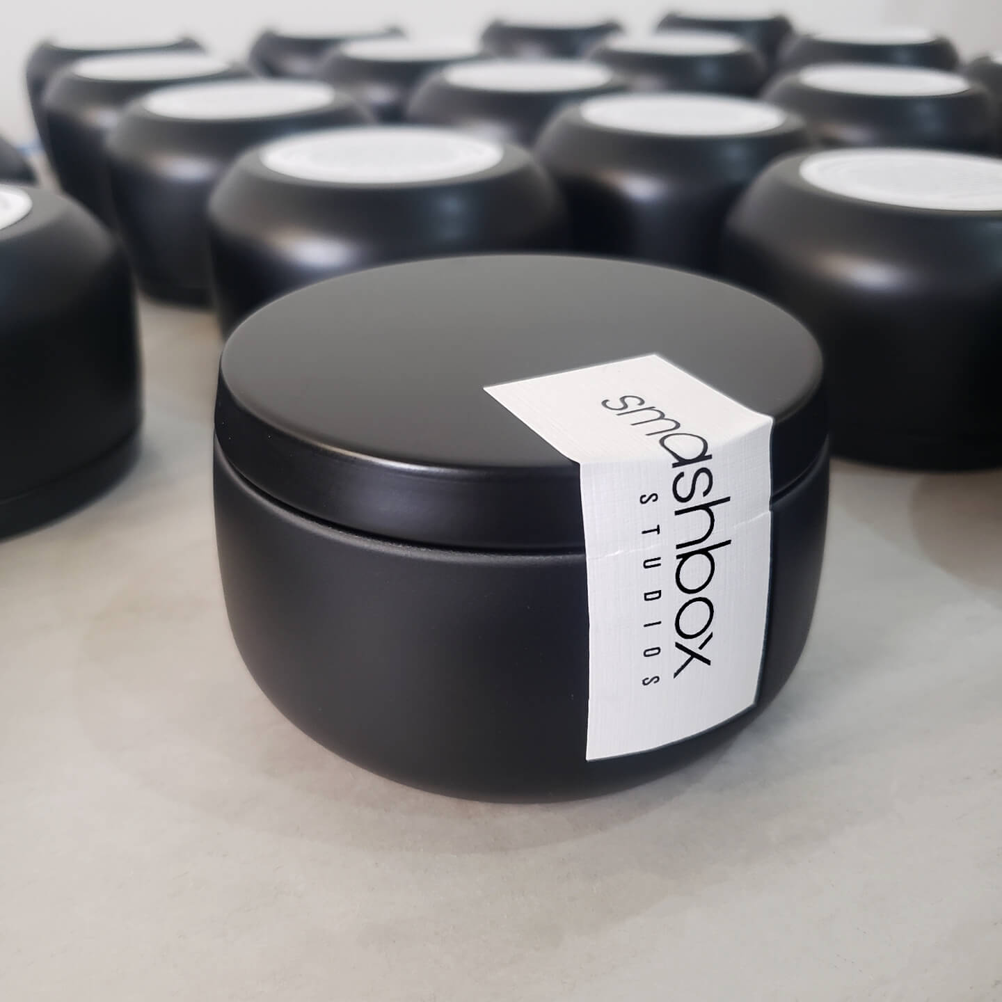 Branded 8oz matte black tin candle with custom label designed for promotions and client gifts.